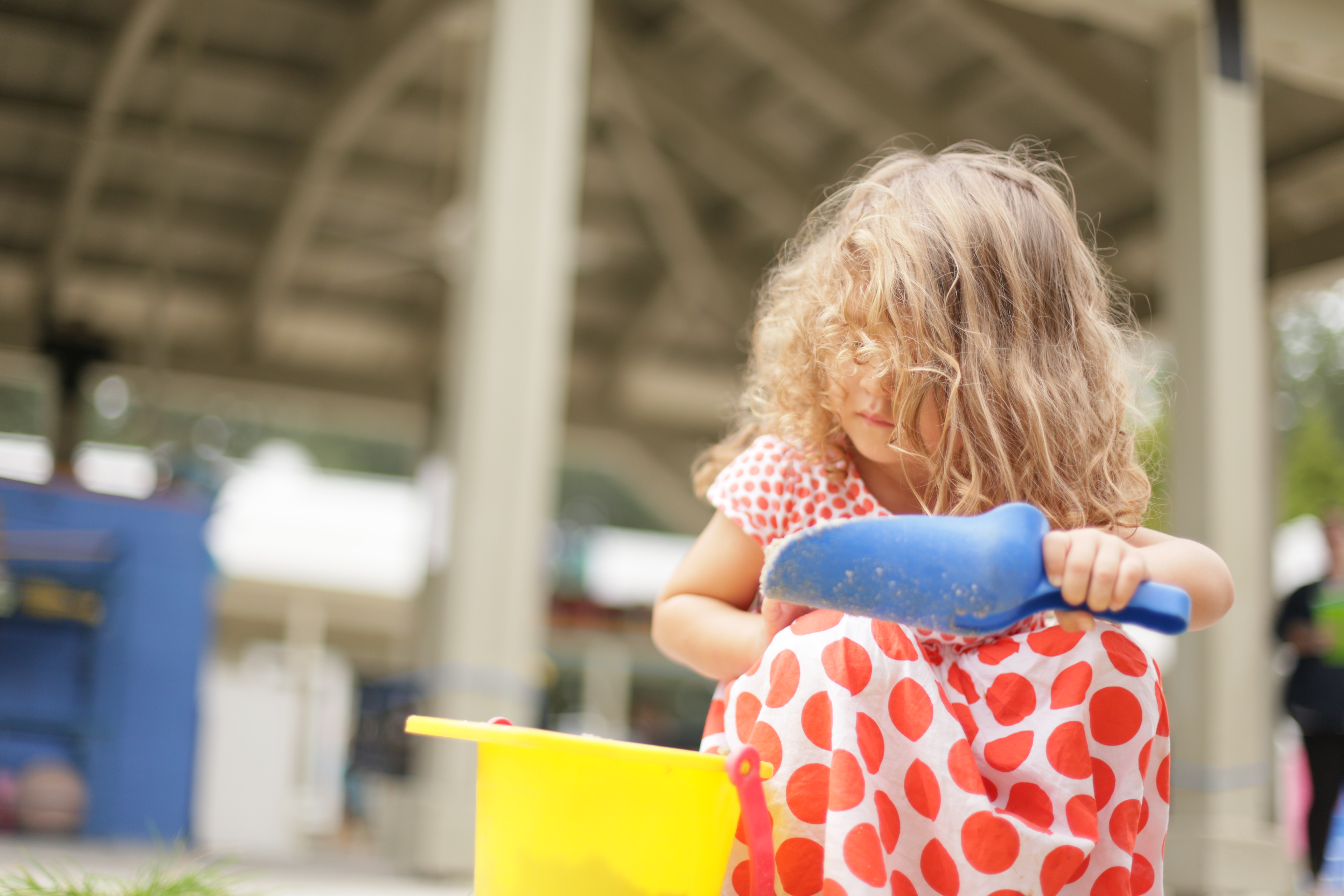 A girl playing with a toy bucket and shovel.