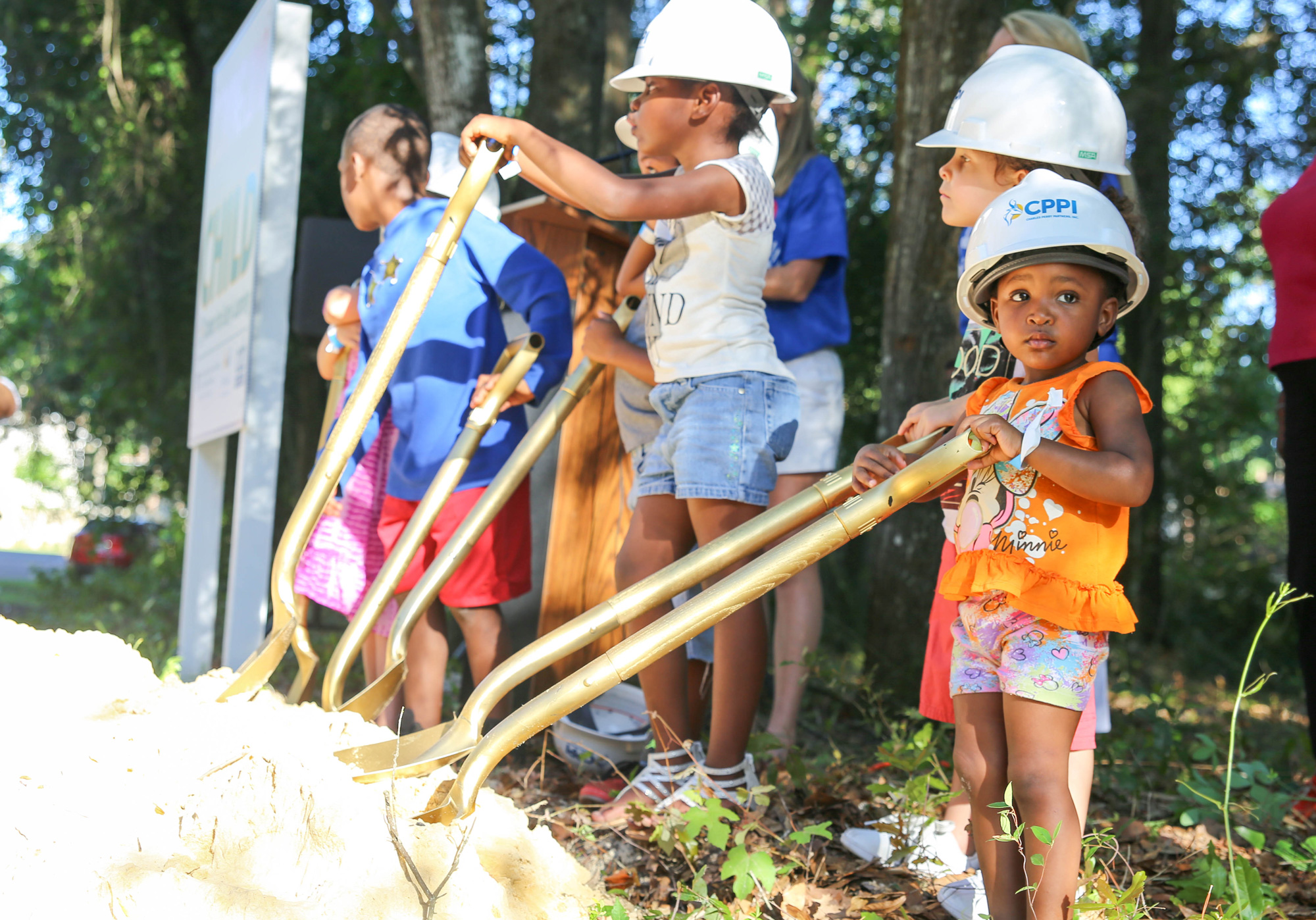 A little girl holding a shovel at a groundbreaking event.