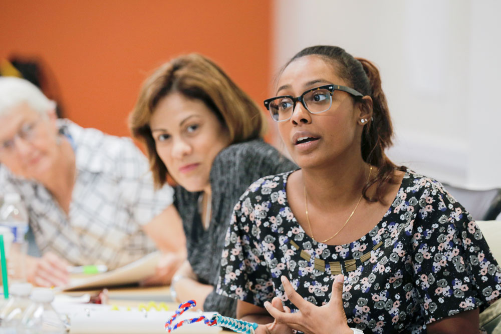 A woman speaking while two others listen.