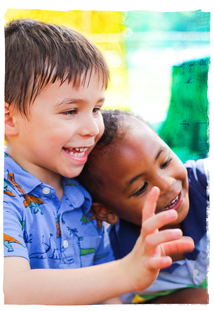 Two young boys laughing and waving together.